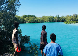 3 young males from broome standing on rocks looking out at water