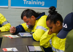 one male and female jobseeker in high vis working on ipads in front of sign that says training