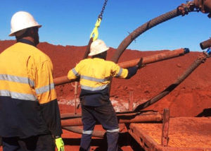2 mining workers on red dirt site lifting piping