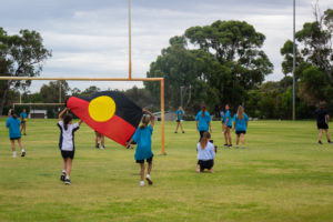 group of deadly sista girlz students playing football on grass oval