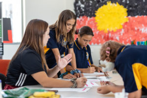 a group of deadly sista girlz students working at their desks in front of aboriginal flag