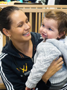 adult female smiling and holding baby