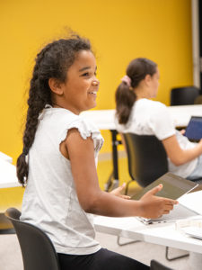 female child smiling and playing on laptop